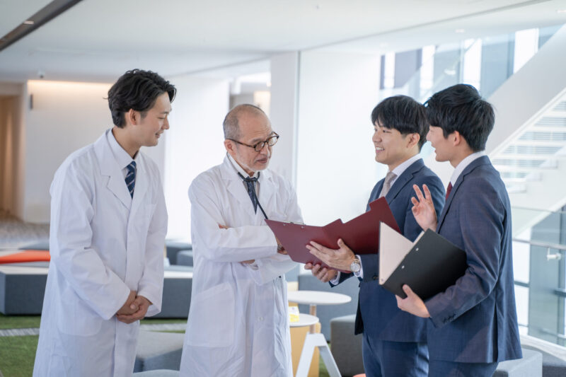 a male doctor and a medical information representative mr talk with smiles at the hospital.