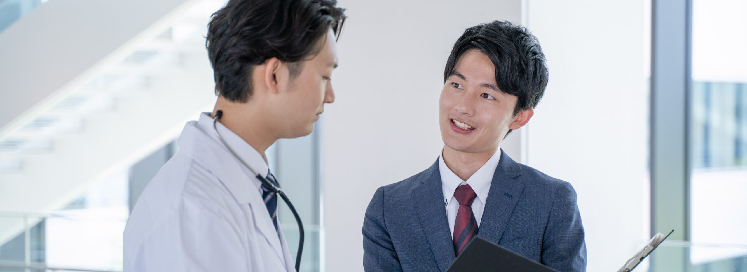a male doctor and a medical information representative mr talk with smiles at the hospital.